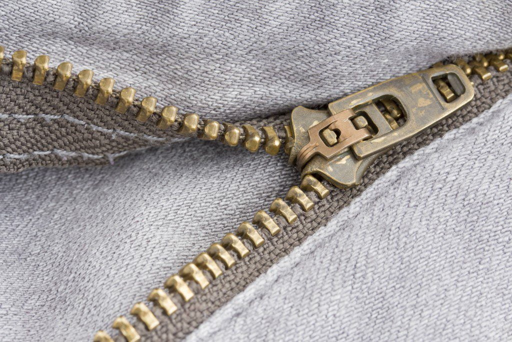 Close-up of a brass zipper on gray fabric